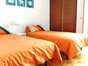フォス・ド・アレーリョにあるFoz do Arelho Beach Apartment "Blue"のオレンジ色のベッド2台が備わる客室です。