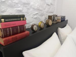 uma prateleira com livros e relógios ao lado de uma cama em casa do castelo em Alegrete