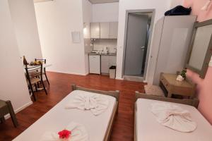 salon z 2 białymi stołami i kuchnią w obiekcie Vasilakis Studios & Apartments w mieście Stalida