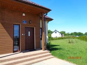 a house with a wooden door and a grass yard at Domek w Dolinie Teczy in Dębina