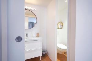 a white bathroom with a sink and a mirror at Chemin des Ormeaux in Ennezat
