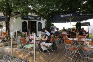 a group of people sitting at tables outside a restaurant at Pension Zum alten Gasthaus Hänsel in Krauschwitz