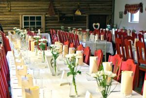 una mesa larga con sillas rojas y flores blancas. en Eräjärven Eerola aittahuone (summer room), en Eräjärvi