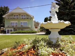 a white fountain in front of a house at Elisoria Apartments in Cserszegtomaj
