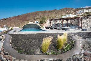 a swimming pool in a yard with a table and a bench at Sophia Finikia Villas in Oia
