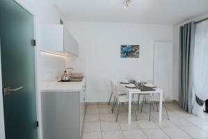 a white kitchen with a white table and chairs at Apartamenty Niezapominajka in Poronin