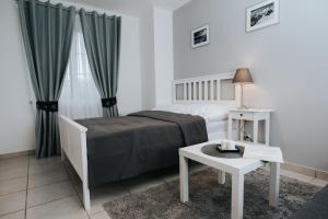 a white bedroom with a bed and a table at Apartamenty Niezapominajka in Poronin