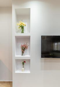 a living room with white shelves with flowers and a tv at Kamis Suite in Neos Marmaras