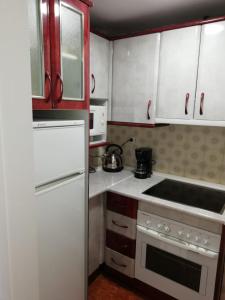 トレモリノスにあるCentral Large Studio Torremolinosの小さなキッチン(白い家電製品、赤いキャビネット付)