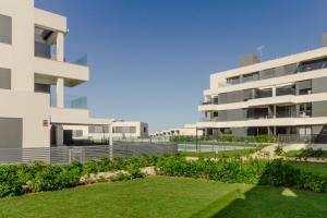 Un gran edificio con césped delante. en Apartamentos Bahía Blanca, en El Puerto de Santa María