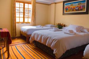 a hotel room with two beds and a window at Tumy house B&B in Ollantaytambo