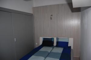 uma cama com almofadas azuis num pequeno quarto em Apartman a Szentlélek u. -3ban em Sopron