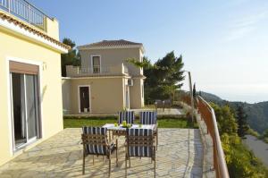 eine Terrasse mit Stühlen, einem Tisch und einem Haus in der Unterkunft Sun Gazing Villas in Drymon