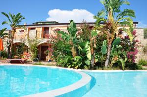 a swimming pool in front of a house with plants at Residence Baia Infreschi in Marina di Camerota