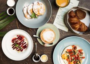 a table topped with plates of breakfast foods and coffee at WYNWOOD Hotel in Saint Petersburg
