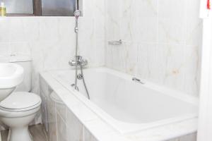 a bathroom with a white tub and a toilet at Streets of Gold Guest House in Gaborone