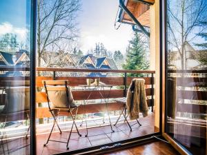 een stoel op een balkon met een groot raam bij TatryTOP Apartamenty Kaszelewski in Zakopane