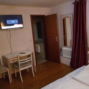 a room with a bed and a desk and a television at Hotel Südheide in Hermannsburg