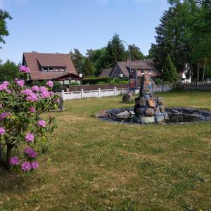 a statue in the middle of a yard with flowers at Hotel Südheide in Hermannsburg