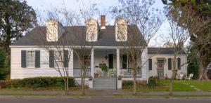 a white house with trees in front of it at Magnolia Cottage Bed and Breakfast in Natchez