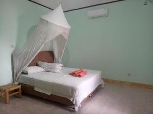 a bedroom with a white bed with a canopy at Krisna Bungalows and Restaurant in Sekotong