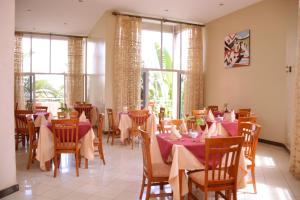 a dining room with tables and chairs and windows at Beausejour Hotel in Kigali