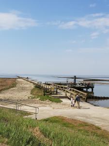 a group of people walking on a beach near a pier at Kleines Häuschen am Deich, vor den Toren von Sylt in Emmelsbüll-Horsbüll