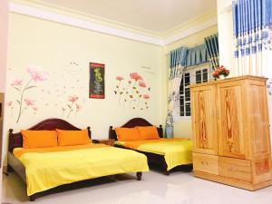 two beds in a room with yellow sheets and orange pillows at Pensee Guesthouse in Da Lat