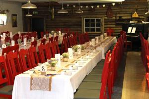 a long table in a room with red chairs at Eräjärven Eerola Guesthouse in Eräjärvi