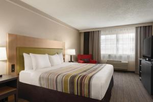 a hotel room with a bed and a television at Country Inn & Suites by Radisson, Chicago-Hoffman in Hoffman Estates