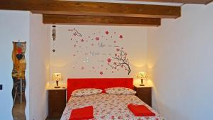 una camera da letto con un letto rosso e fiori sul muro di Casa Paola Holiday studio by Gardadomusmea a Tremosine Sul Garda