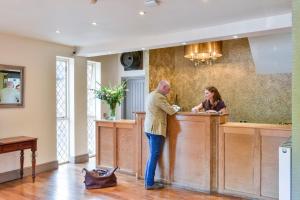 a man and a woman standing at a counter at The Charlecote Pheasant in Stratford-upon-Avon