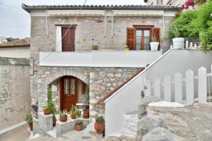 a stone house with a white fence and potted plants at Kassandra House in Hydra