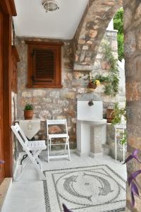 a patio with a table and chairs and a stone wall at Kassandra House in Hydra
