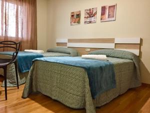 Tres camas en una habitación con mantas azules. en De Camino vivienda de uso turístico, en Arzúa