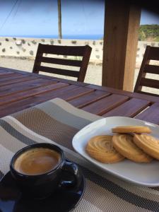 une assiette de biscuits et une tasse de café sur une table dans l'établissement Fajazinha Cottage, à Faja Grande