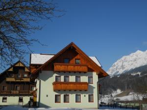 a building in the snow with mountains in the background at Pension Thorerhof in Haus im Ennstal