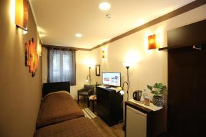 ペーチにあるNapraforgó Wellness Ház és Panzióのベッド1台とテレビが備わる小さな客室です。