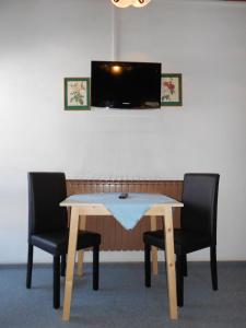 a table with two chairs and a television in a room at Pension Thorerhof in Haus im Ennstal