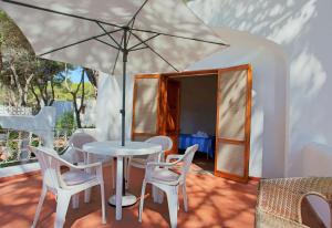 una mesa, sillas y una sombrilla en el patio en Ville Campo Verde by TerraSalento, en San Cataldo