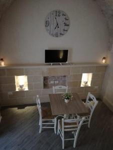 una sala da pranzo con tavolo e orologio sul muro di La Casedda di pittali a Carovigno