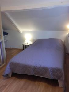 1 dormitorio con 1 cama grande con colcha púrpura en Chambre d'hôtes La Guéjaillière, en Beaumont-Pied-de-Boeuf