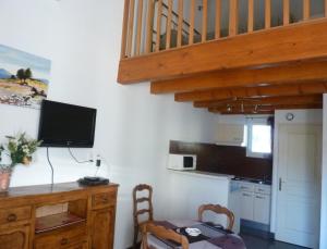 a kitchen with a table and a desk with a television at Appart'Hôtel Les Rochers in Auriol