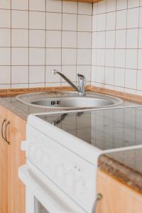 ein Waschbecken in einer gefliesten Küche mit einer Theke in der Unterkunft Apartament Gdynia Centrum in Gdynia