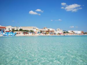 a beach with a group of people in the water at Eolo Casa Vacanze in Torre Lapillo