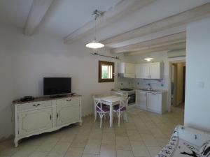 a kitchen with a table and a tv in it at La Corte degli Ulivi Appartamenti in Cala Liberotto