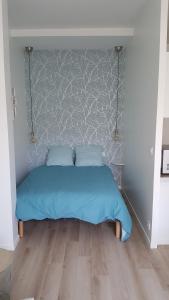 a bed with a blue comforter in a bedroom at Studio Winston in Dinard