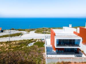 an orange building with the ocean in the background at Casa das Barcas in Lourinhã