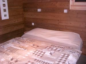 Cama en habitación con pared de madera en Chalets les Marcels, en La Bresse