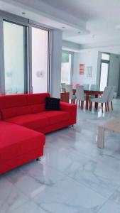 un divano rosso in una stanza con tavoli e sedie di Villa Spathele a Paralimni